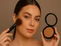 Kobieta z pędzlem nakłada bronzer w kamieniu, by uzyskać naturalny efekt muśniętej słońcem skóry.