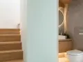 Escaliers en bois menant à un wc sous pente moderne, avec lavabo et miroir rond.