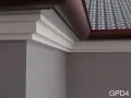 Elegancki gzyms zdobi narożnik budynku, harmonizując z dachówką i rynną.