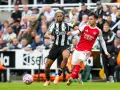 Piłkarze Newcastle i Arsenal walczą o piłkę na boisku. Intensywna akcja podczas meczu.