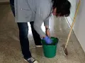 Sprzątaczka w szkole, w niebieskich rękawiczkach, przygotowuje się do pracy. Zastanawiasz się, ile zarabia sprzątaczka w szkole?