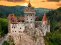 Majestatyczny zamek w Transylwanii, górujący nad lasami o zachodzie słońca.