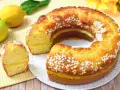 Un soffice ciambellone al limone, con una golosa crema gialla all'interno e decorato con perline di zucchero. Perfetto per la colazione o la merenda.