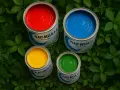 Latas de pintura roja, azul, amarilla y verde listas para pintar plástico.
