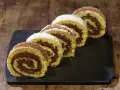 Fette di rotolo alla nutella cosparse di zucchero a velo e cacao, su una lavagna scura, pronte per essere gustate.