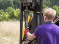 Mężczyzna w czerwonej rękawicy trzyma wiertło. Czy to geolog? Pracuje przy maszynie wiertniczej w terenie.