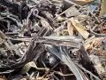 Góra złomu, poskręcane metalowe elementy, tworzące chaotyczną strukturę. Widoczne fragmenty blachy, prętów i innych odpadów. Kod odpadu: 17 04 05.