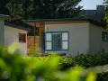 Nowoczesne domki letniskowe w osadzie Chmielaki. Jasne ściany, niebieskie okna i drewniane elementy tworzą przytulną atmosferę.