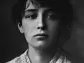 Portret młodej Camille Claudel, zamyślonej, z delikatnym uśmiechem.
