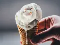 Eine Hand hält ein schmelzendes Rhabarber-Eis in einer Waffel.
