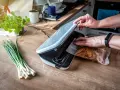 Ręce zamykają zgrzewarkę próżniową, pokazując, jak działa zgrzewarka próżniowa, przygotowując kurczaka do przechowywania.