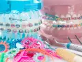 Kolorowe ligatury i metalowe zamki na modelach szczęk, obok narzędzi dentystycznych. To aparat ceramiczny w akcji!