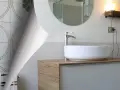 Un bagno anni '70 con piastrelle floreali verdi e un moderno lavabo.