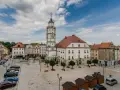 Rynek w Paczkowie, polskie Carcassonne, z ratuszem i wieżą. Brukowany plac, samochody, ławki i małe drewniane budki.