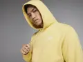Młody mężczyzna w żółtej bluzie z kapturem Nike Club.