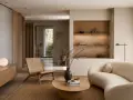 Salón de **estilo Japandi** con sofá curvo, silla de ratán, mesa de centro de madera y estanterías empotradas.