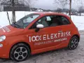 Pomarańczowy Fiat 500e w zimowej scenerii, z napisem "100% ELEKTRISK". Sprawdź zasięg tego elektryka!