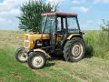 Żółty Ursus C-360 na łące. Pytanie o to, ile oleju do filtra powietrza C-360, jest kluczowe dla jego sprawnej pracy.