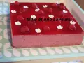 Un délicieux bavarois fruits rouges, orné de framboises fraîches et de petites fleurs blanches, promet une explosion de saveurs.