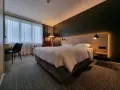 Przytulny pokój w Park Inn Papenburg: wygodne łóżko, designerskie lampy i okna z zasłonami.