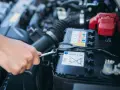 Mano con chiave inglese che inizia a staccare batteria auto.