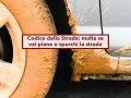 Ruota e carrozzeria di un'auto ricoperte di fango. Il testo recita: "Codice della Strada: multa se vai piano o sporchi la strada".
