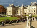 Palacio de Luxemburgo y su jardín con gente sentada y un monumento.
