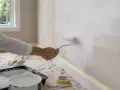 Application d'une sous-couche blanche au rouleau. Le temps de séchage est crucial avant la couche de finition.