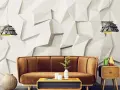 Sofá marrón y mesa de centro con elementos decorativos frente a una pared con relieve que combina papel pintado y pintura.