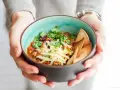 Miseczka pysznego chili con carne przepis, posypana serem i świeżą kolendrą, z chrupiącymi nachos. Idealne na chłodne dni.