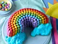 Bunter regenbogen kuchen, verziert mit vielen bunten Smarties und blauer Zuckerwatte als Wolken. Ein Fest für die Augen!
