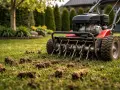 Właśnie trwa aeracja trawnika. Widoczna jest maszyna z obracającymi się kolcami, która usuwa z gleby darniowe wałeczki, poprawiając jej strukturę.