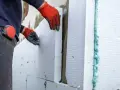 Operaio posa pannelli isolanti per cappotto termico, attenzione alle fughe e alle soglie per evitare ponti termici.