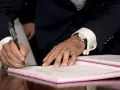 Mężczyzna w garniturze podpisuje dokument, co może oznaczać rozwiązanie umowy zlecenia za porozumieniem stron.