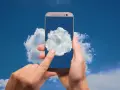Dłonie trzymają telefon, na którego ekranie widać chmurę. Czy to właśnie tam jest chmura w telefonie?