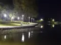Nocny spacer nad zalewem Wolbromskim. Latarnie oświetlają ścieżkę i ławki, odbijając się w spokojnej tafli wody.