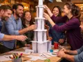 Une équipe s'amuse lors d'une activité séminaire entreprise, construisant une tour en papier. Collaboration et rires garantis !
