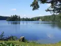 Ein ruhiger Lippstadt See mit bewaldeten Ufern und einem kleinen Haus am Horizont.