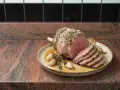 Rôti d'agneau sans os au four, tranché, avec ail et herbes. Le temps de cuisson parfait pour un plat savoureux.