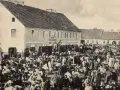 Tłum ludzi na targu w Biłgoraju, jakby żywcem wyjęty z legendy o tym mieście. W tle budynki i stragany.