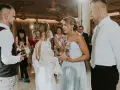 Nietypowe podziękowania dla rodziców na weselu: panna młoda z bukietem w szkle i pan młody z prezentem.
