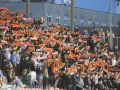 Tłum kibiców na stadionie z szalikami w barwach pomarańczowo-czarnych. Widać napisy "Chrobry" i "Chrobry Głogów".