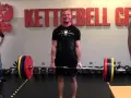 Man i gymmet förbereder sig för ett styrkelyft program. Han håller i en skivstång med vikter.