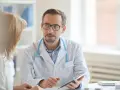 Arzt erklärt Patientin Ergebnisse, vielleicht den lipase wert, auf einem Tablet.