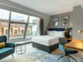 Nowoczesny pokój hotelowy z dużym oknem i widokiem na dachy. Czy zeby zarezerwowac hotel ttzna miec 18 lat? Tak, zazwyczaj.