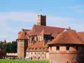 Zamek w Malborku, wpisany na listę **UNESCO Polska**, to imponująca twierdza z czerwonej cegły z charakterystycznymi wieżami i dachami.