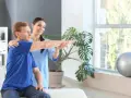 Ein Physiotherapeut unterstützt einen Patienten bei der Armbewegung.