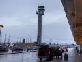 Wieża kontrolna na oslo lotnisko. Ludzie z bagażami wsiadają do vana.