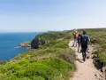 Randonneurs sur le sentier côtier GR34, profitant de la vue sur la mer et les falaises. La distance semble longue, mais le paysage est magnifique.