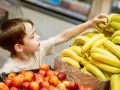 Chłopiec sięga po banana. Co zrobić, gdy dziecko kradnie w sklepie? Rozmowa i nauka uczciwości to klucz.